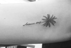 a woman's arm with a small palm tree tattoo on the left inner arm