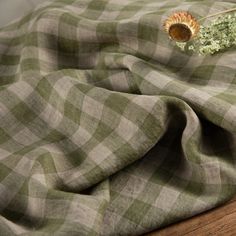 a green and white checkered blanket with a dried flower on it's end