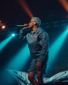 a man standing on top of a stage holding a microphone in his hand and singing