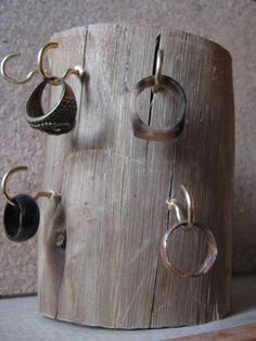 there is a wooden holder with rings and earring hooks on the top of it