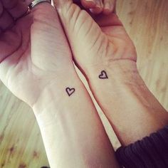 two people holding hands with tattoos on their arms and one has a heart in the middle