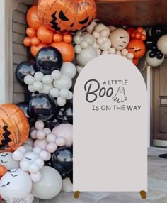 a bunch of balloons that are in front of a door with the words boo is on the way