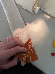 someone is cutting paper with scissors on a counter top next to an orange and white object