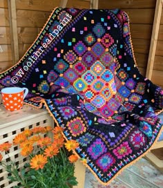 a crocheted blanket sitting on top of a table next to flowers and a cup