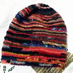 a multicolored knitted hat sitting on top of a pile of bamboo sticks