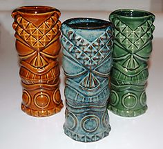 four different colored vases are lined up on the counter top, each with an intricate design