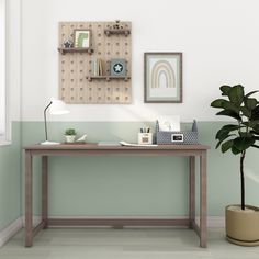 a desk with a potted plant next to it and two pictures on the wall