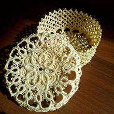 two crocheted doily sitting on top of a wooden table next to each other