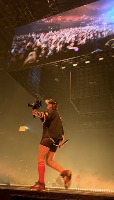 a man standing on top of a stage while holding a camera in his hand and wearing tights