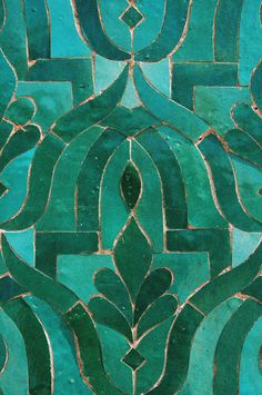 a close up view of a green and blue tile pattern with an intricate design on it