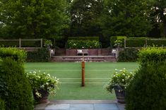 a tennis court surrounded by bushes and trees