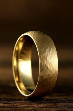 a gold wedding ring on top of a wooden table