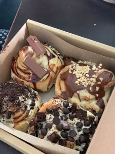 a box filled with lots of different flavored donuts on top of a table