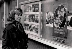 a woman standing in front of a movie poster on the side of a train car