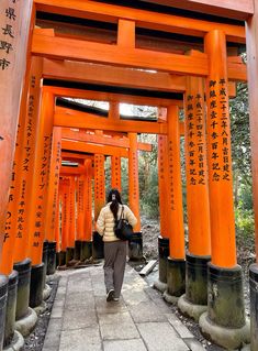 a person walking under an orange structure with writing on it