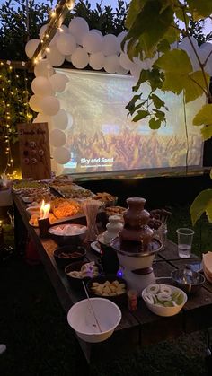 an outdoor movie screen is set up with food and drinks in front of the screen