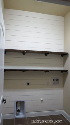 an empty bathroom with white walls and shelves