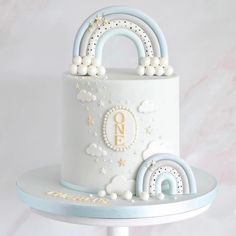 there is a white cake with blue and gold decorations on the top it has a rainbow decoration