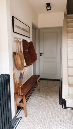 an entryway with a bench and two purses hanging on the wall next to it