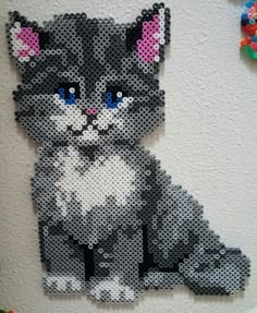 a black and white cat made out of legos on a wall with beads around it