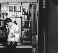 a woman standing in front of a bookshelf with lots of books on it