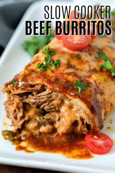 an enchilada on a plate with tomatoes and parsley