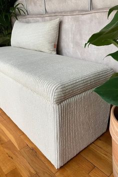 a white bed sitting on top of a wooden floor next to a plant