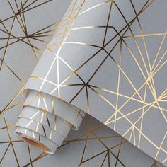 a wallpaper with gold lines on it and a grey paper roll next to it