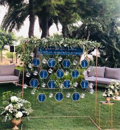 an outdoor seating area decorated with blue and white flowers, greenery and hanging glass globes