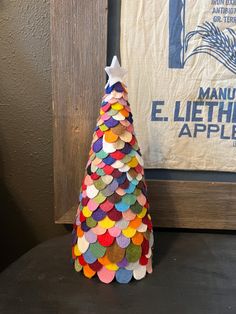 a paper mache christmas tree sitting on top of a table next to a sign