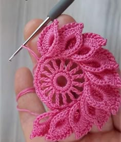 the crochet flower is being worked on by someone using a needle to make it