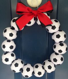 a wreath made out of soccer balls with a red bow hanging on the front door