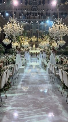 an elaborately decorated wedding venue with chandeliers and white flowers on the ceiling