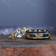 two wedding rings sitting on top of a wooden table next to each other with green and gold accents