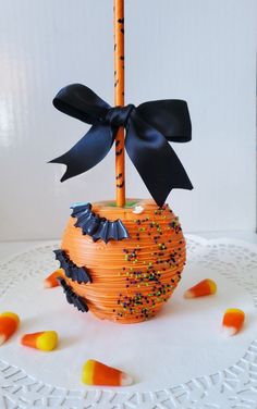 an orange pumpkin shaped basket with black bow and candy on it, sitting on a white surface