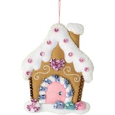 a gingerbread house ornament hanging from a string with pink and blue decorations