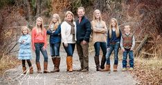 a family standing on a path in the woods with their arms wrapped around each other