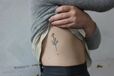 a woman's stomach with a small flower tattoo on it