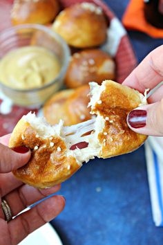 a person holding a pastry in their hand and dipping sauce on the other side for dipping