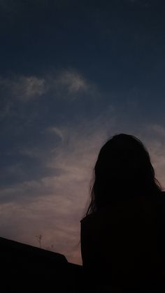 the silhouette of a woman with her hair blowing in the wind, against a purple and blue sky