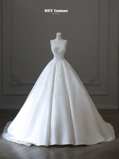 a white wedding dress on display in front of a gray wall with the words hey couture