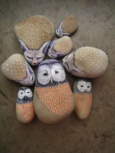 an arrangement of painted rocks with owls and cats sitting on top of one another in the middle