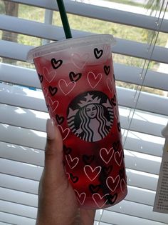 someone holding up a starbucks cup with hearts on it