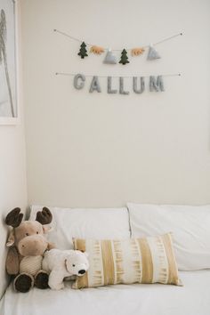 two stuffed animals sitting on top of a bed next to a wall hanging above it