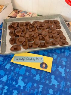 there is a tray of cowboy hats on top of a blue table cloth with a name tag