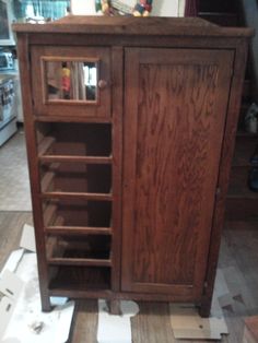 a wooden cabinet sitting on top of a hard wood floor next to a pile of cardboard