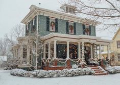 a large house covered in snow with wreaths on the front porch and steps leading up to it