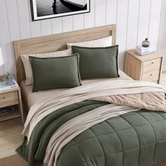 a bed with green and white comforters in a room next to a lamp on a table