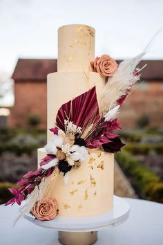 a wedding cake decorated with flowers and feathers