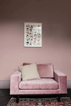 a pink couch sitting in front of a wall with pictures on the wall above it